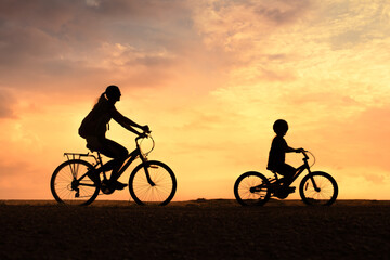 Obraz premium Parent and Child Riding Bikes Together at Sunset 