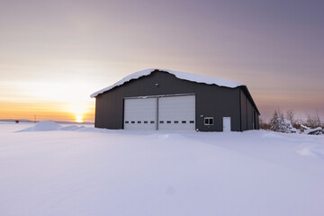 Warehouse in snow, industrial building in sunset light in winter.