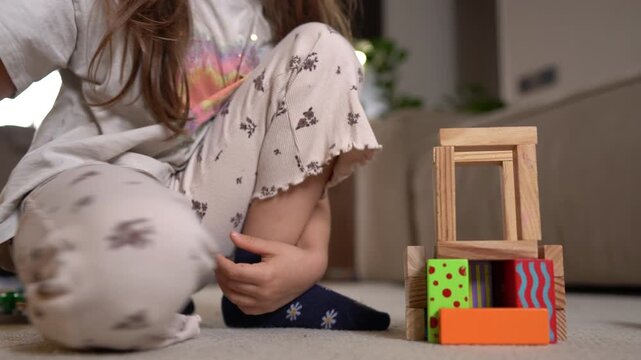 Child engaged in tactile play with wooden blocks on carpet