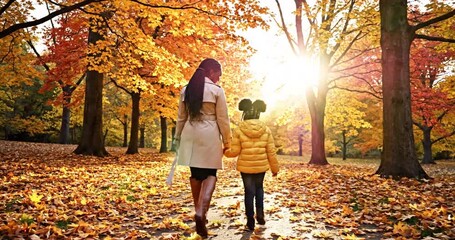 A mother and daughter stroll through a vibrant autumn park, enjoying the colorful foliage