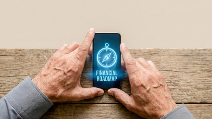Financial roadmap high level planning concept guidance for retirement on mobile phone screen held by senior hands on rustic wooden table