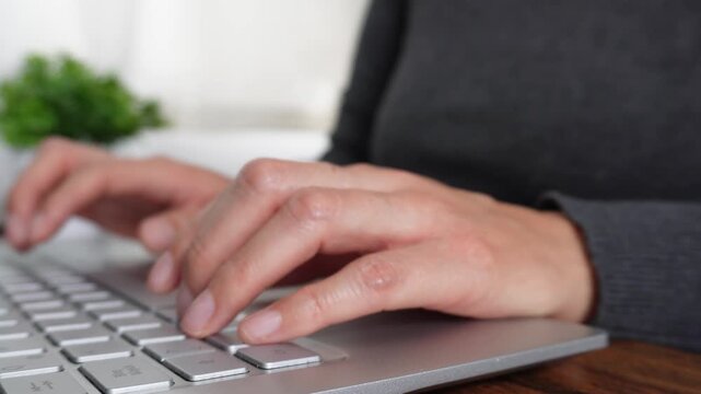 A woman is typing on a keyboard with her hand on the space bar. Concept of productivity and focus, as the woman is likely working on a task or project. The keyboard is positioned on a wooden desk