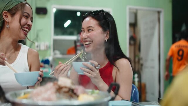 Two cheerful asian friends eating traditional thai barbecue