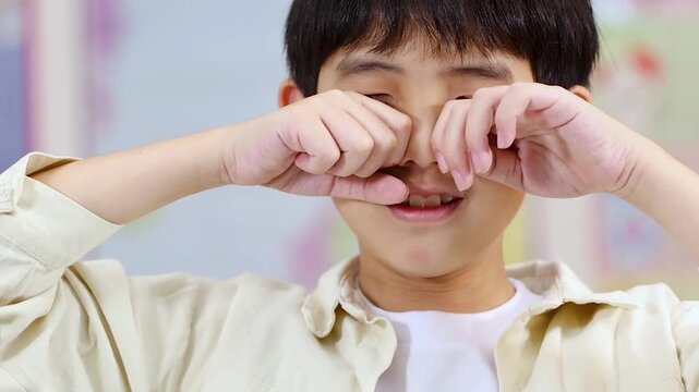 Close-up of Upset Asian Boy Rubbing His Eyes While Crying
