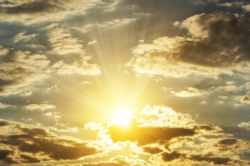 Beautiful golden sunset sky with dramatic sun rays breaking through clouds. A divine background symbolizing hope, spiritual worship, God's light, and the freedom of soul.