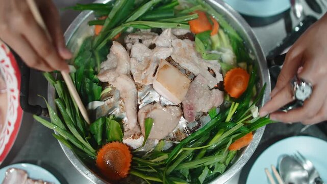 People cooking traditional thai barbecue moo kra ta together