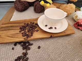 Roasted Coffee Beans Scattered on Wooden Board and Inside a Ceramic Cup for Home Cafe Concept