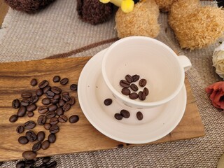 Roasted Coffee Beans Scattered on Wooden Board and Inside a Ceramic Cup for Home Cafe Concept