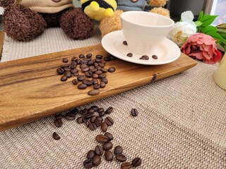 Roasted Coffee Beans Scattered on Wooden Board and Inside a Ceramic Cup for Home Cafe Concept