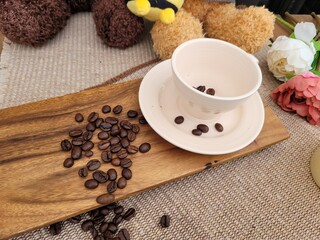 Roasted Coffee Beans Scattered on Wooden Board and Inside a Ceramic Cup for Home Cafe Concept