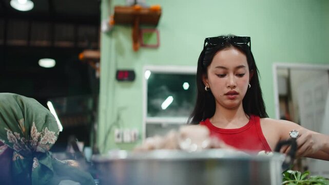 Two young asian friends cooking traditional thai moo kra ta barbecue