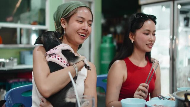 Two thai women eating moo krata at a restaurant