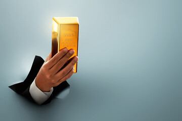 Businessman hand holding shiny gold bar through hole on gray background