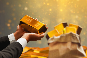 Businessman hand holding shiny gold bar on glowing magic glitter sparkle effect background