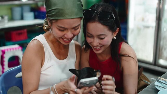 Two cheerful asian friends using a smartphone