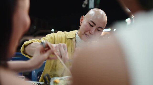 Friends enjoying mookata thai barbecue at a night street food market