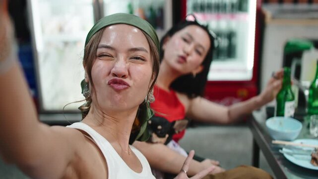 Joyful asian women taking selfie video at restaurant