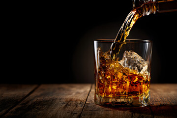 Whiskey Glass with Ice on Wooden Bar Table and Blurred Bar Background