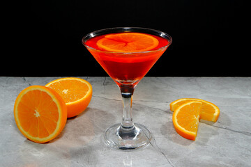 Vibrant orange cocktail with fresh slices on a modern gray surface closeup view