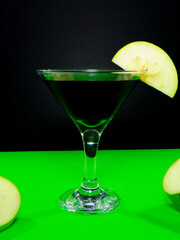Sophisticated green apple martini with fresh slices on vibrant green closeup shot
