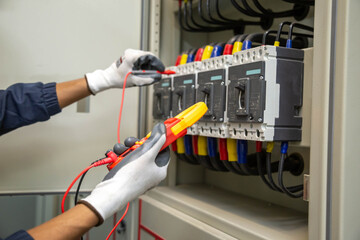 Electrician engineer work tester measuring voltage and current of power electric line in electical cabinet control