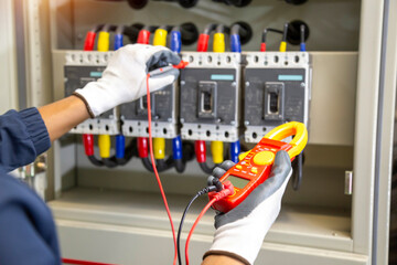 Electrician engineer work tester measuring voltage and current of power electric line in electical cabinet control