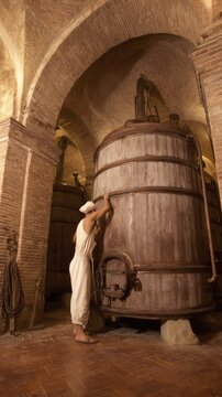 Medieval Brewery Worker Examining Vintage Fermentation Vessel, Warm Interior Ambiance, Traditional Tools, Stone Clad Walls, Attention on the Barrel
