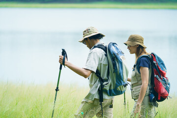 Couple hiking with backpacks near lake. Outdoor adventure and travel lifestyle.