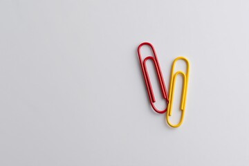 Interlocked red and yellow paperclips on white background office supplies minimalistic design close-up view creative concept