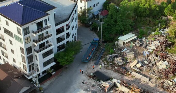 Aerial view of workers unloading rebar from a flatbed truck at a construction site.