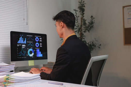 Young businessman analyzing financial data on computer at office - Powered by Adobe