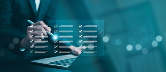 Business executive reviewing large digital checklist on virtual interface using stylus and laptop. Concept of workflow management, task tracking, quality assurance, compliance, audit, and corporate
