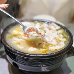 Woman tourist eating Sichuan Fish with Pickled Mustard Greens or Suan Cai Yu in restaurant. Popular foods for tourist eating in Chengdu, Chongqing and China. Chinese Asia and Sichuan foods concept