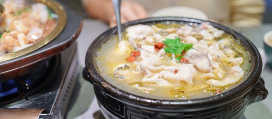 Woman tourist eating Sichuan Fish with Pickled Mustard Greens or Suan Cai Yu in restaurant. Popular foods for tourist eating in Chengdu, Chongqing and China. Chinese Asia and Sichuan foods concept