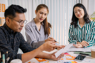 Designers having a UX/UI planning meeting to refine mobile app layouts and user flow. They collaborate closely to create functional and visually appealing interface solutions.