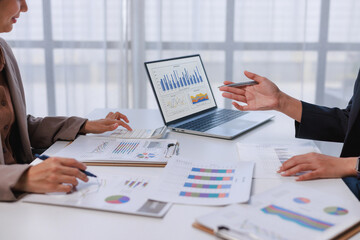 Business professionals analyzing financial data on laptop and reports