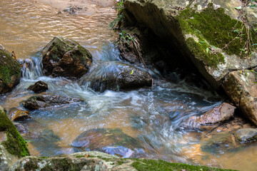 A small, serene waterfall cascades over dark, glistening rocks in a continuous, gentle flow, capturing the pure, raw beauty of nature in motion in Brazil. © AlfRibeiro