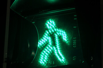 Green light for pedestrians. The "walk" symbol on a traffic signal, indicating it is safe to cross the street. A concept of safety, urban life, and traffic regulation.