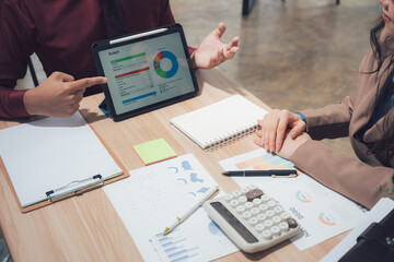 Business Meeting and Presentation: A close-up view captures a dynamic business meeting, where two professionals are deeply engrossed in a financial presentation on a tablet.