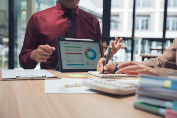 Data analysis meeting: A focused business meeting centers around a tablet displaying data visualizations and charts, where ideas flow freely with engaging discussions and strategic planning. 