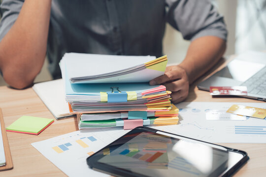 Desk work and study: In this image, a person at a desk is reviewing documents, with a tablet and other materials surrounding him, possibly studying or engaged in office work. 