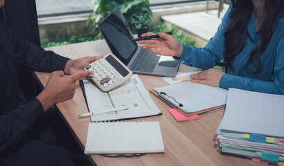 Financial Synergy: A dynamic business meeting unfolds, where individuals collaborate on complex financial matters using a calculator and data, symbolizing insightful strategy and fiscal harmony.