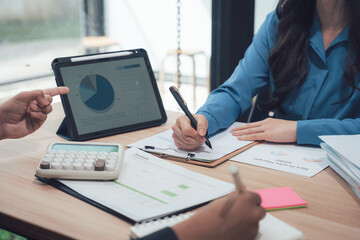 Business Strategy: Close-up of hands, a tablet displaying financial analysis, and documents underscore strategic planning and teamwork.