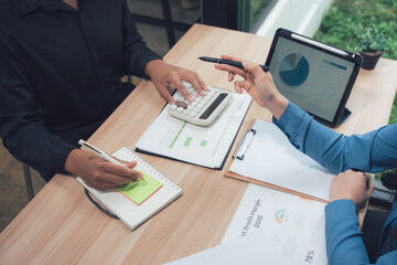 Financial Consultation: Two professionals collaborate, reviewing financial data with a calculator and tablet. Analysis and planning.