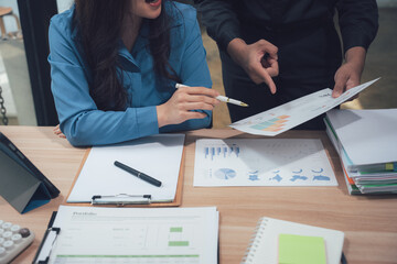 Strategic Discussion: Two professionals, focused and engaged, review financial documents during a crucial meeting. The image captures collaboration and detailed analysis.