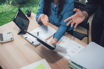 Business Collaboration: A high-angle view showcases two professionals engaged in a focused business meeting, examining documents and using technology for enhanced collaboration.