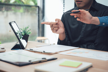 Business Discussion at the Desk: Two professional individuals are immersed in a focused discussion at their work desk, a tablet and documents spread before them.