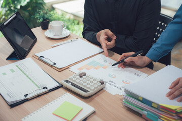 Analyzing Charts: Two business professionals engaged in collaborative analysis, focused on charts, graphs, and financial data in an office setting. They are studying data. 