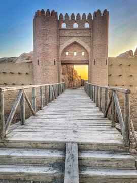 Restored entrance to the medieval fortress city of Sauran in Kazakhstan&rsquo;s desert steppe, with brick gates, earthen walls, and a wooden bridge in a historic Silk Road setting.