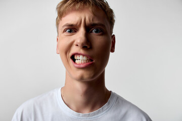 Closeup of an angry, frustrated man with clenched teeth and wide eyes, conveying intense emotion,...